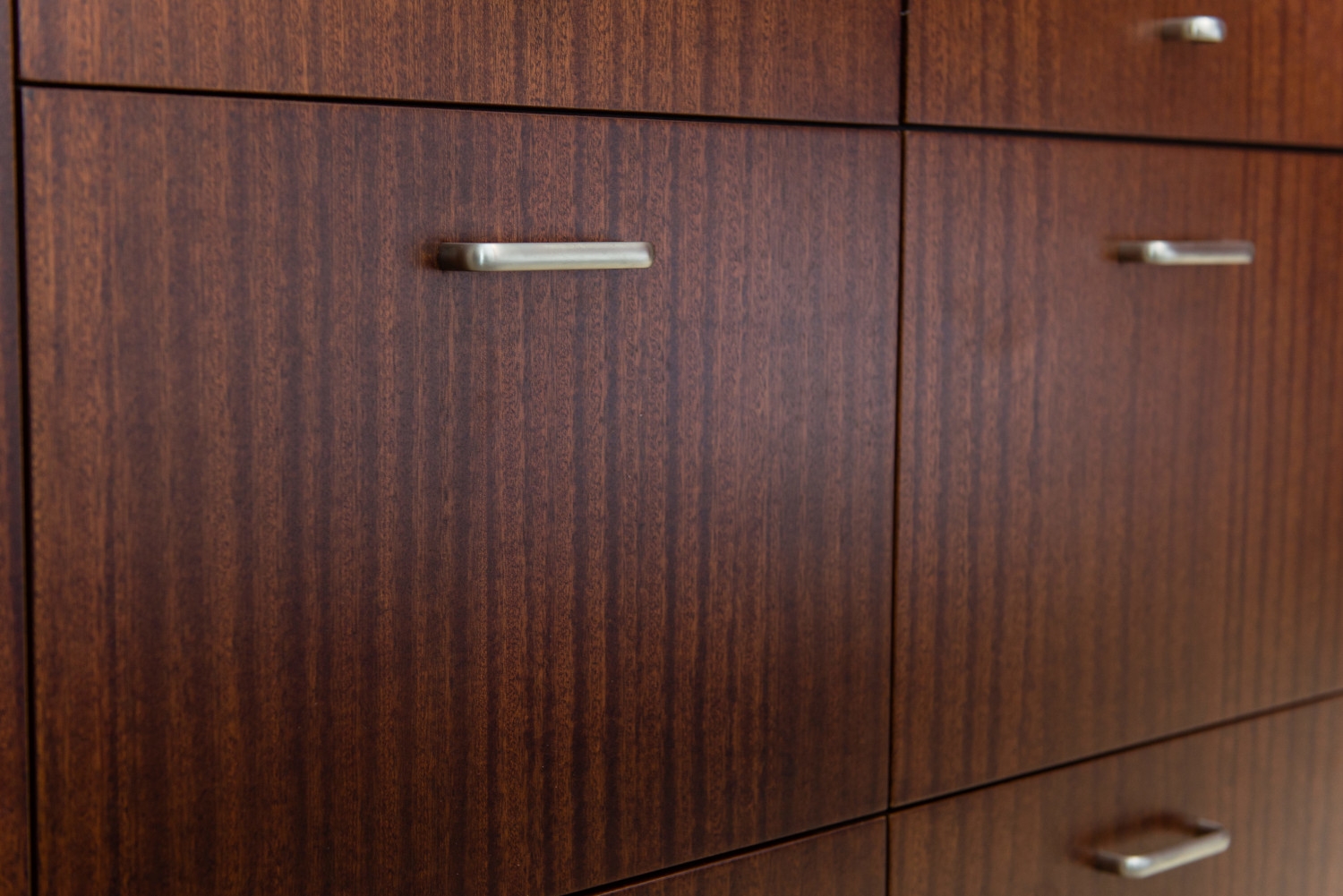 Detailed view of modern kitchen cabinet doors showcasing the rich wood grain texture and seamless construction, creating a sophisticated and stylish look