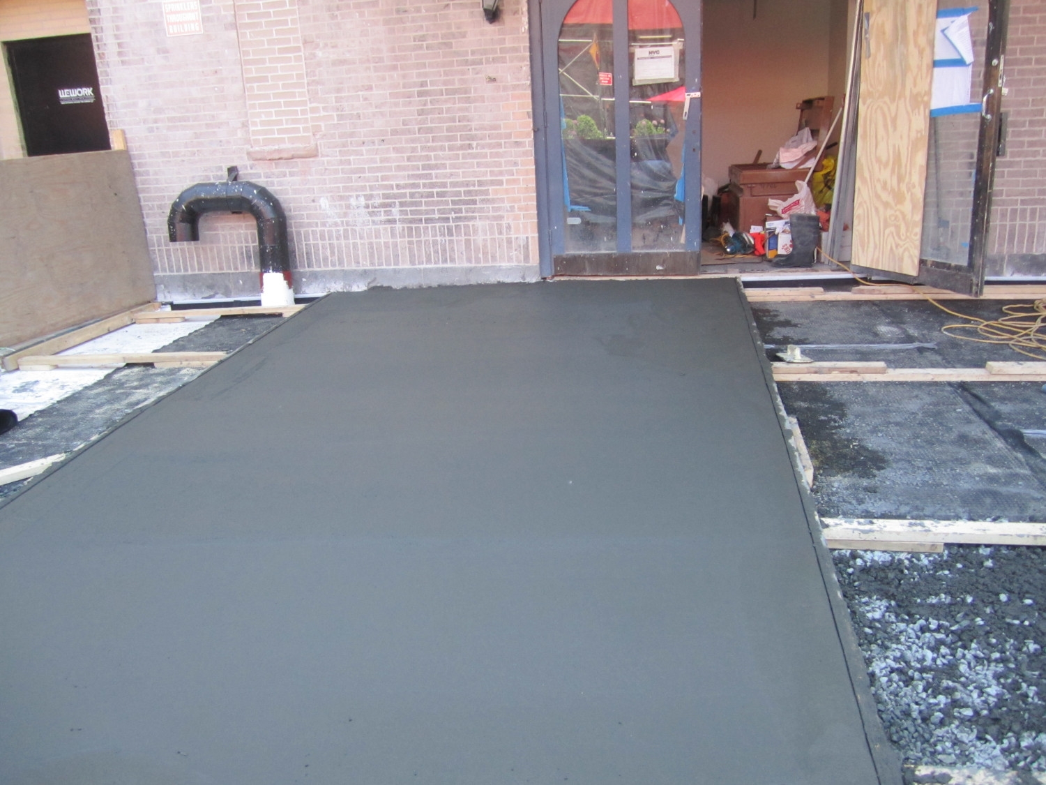 Work-in-progress image of a large 10x25 foot concrete sidewalk replacement in New York City, showcasing the curing concrete, expansion joints, and form work expertly handled by Jepol Construction.