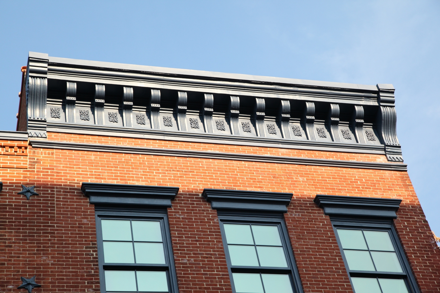 Top level view of a New York City building showcasing Jepol Construction's high-quality craftsmanship in exterior renovation, including cornice replacement, brickwork, and ornamental window lintel restoration.