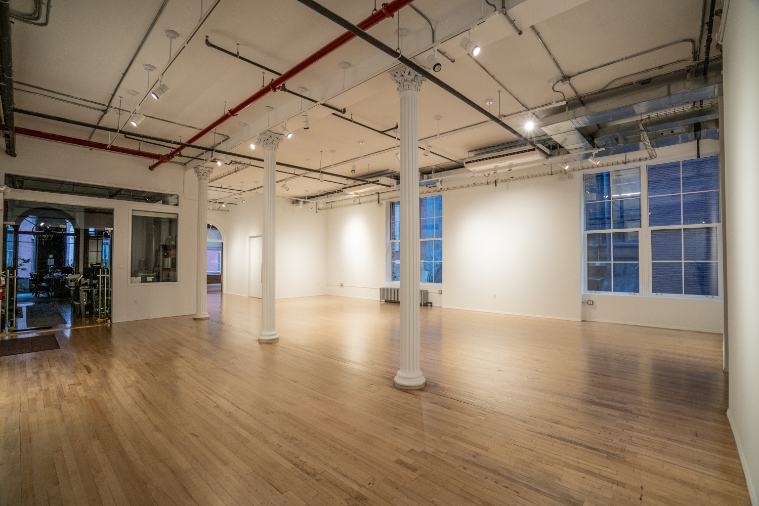 Inside view of 80 White Street displaying the restored steel columns, freshly refinished wood floors, and newly installed gypsum partitions. The image highlights the interior finishes, such as painting, new lighting, sprinkler systems, elevator door trims, windows, fire alarm, ductwork, and steel hollow metal doors.