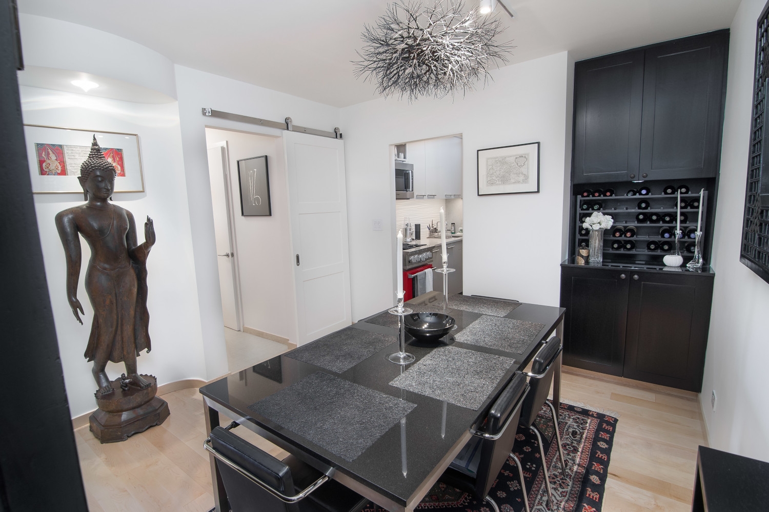 Renovated apartment in Manhattan showcasing the dining room with Japanese art, a small wine cabinet, a new dining set, new wood flooring, a barn door, and painted walls