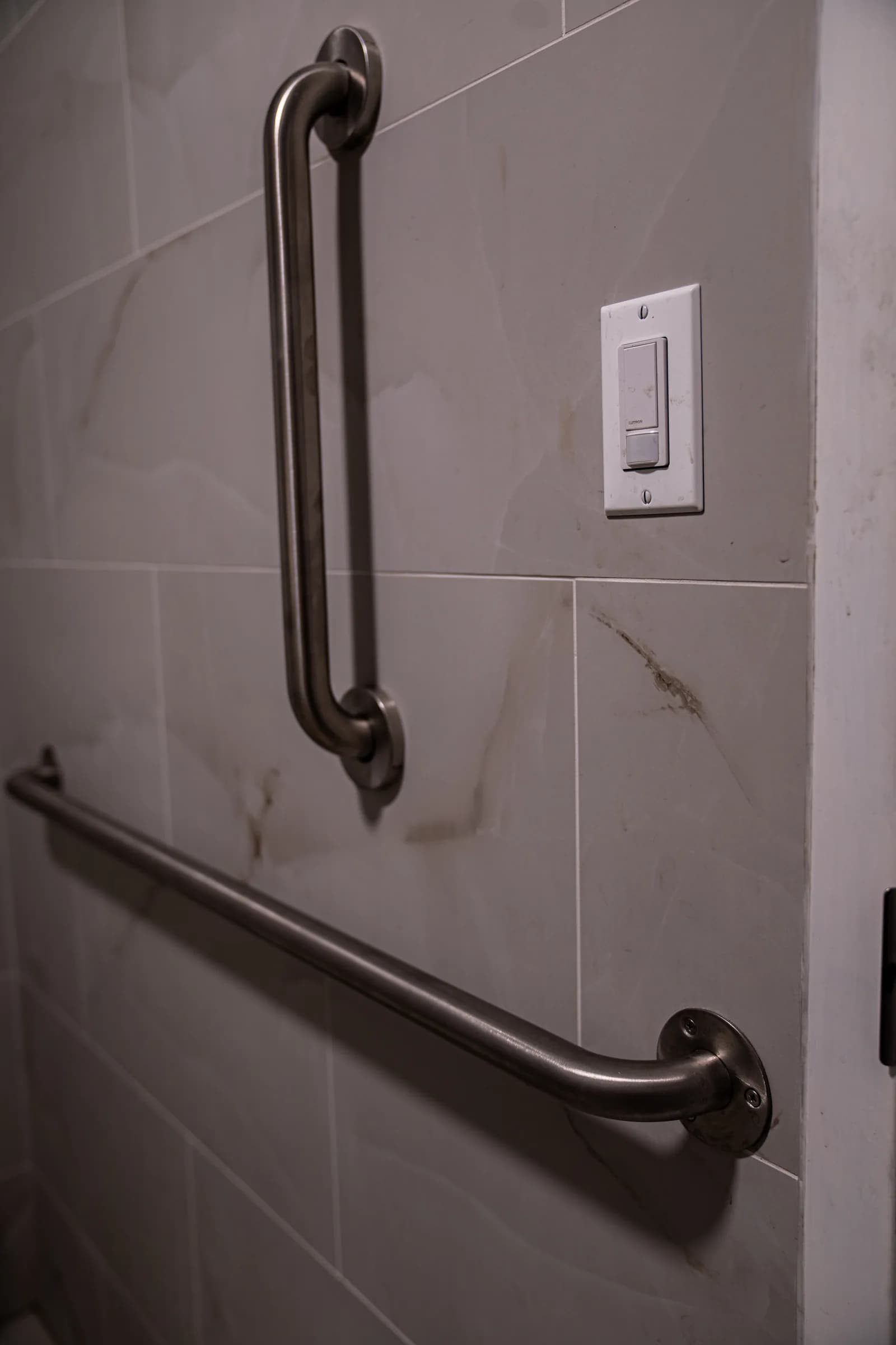 Accessibility grab bars installed against the tiled restroom wall
